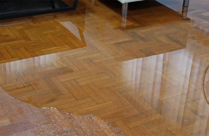 water spreading flooding on living room parquet floor in a house damage caused by water leakage